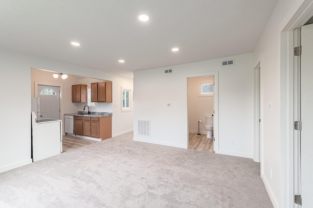 607 S Mill St, Saint Louis, MI 48880 - kitchen featuring light carpet, brown cabinets, washer / clothes dryer, a sink, and recessed lighting