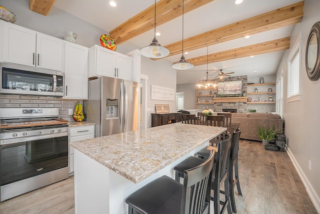 1749 Fairview Dr, Allegan, MI 49010 - kitchen featuring appliances with stainless steel finishes, a ceiling fan, light wood finished floors, decorative backsplash, and beam ceiling