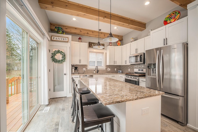 1749 Fairview Dr, Allegan, MI 49010 - kitchen featuring stainless steel appliances, tasteful backsplash, light wood-type flooring, a center island, and white cabinetry
