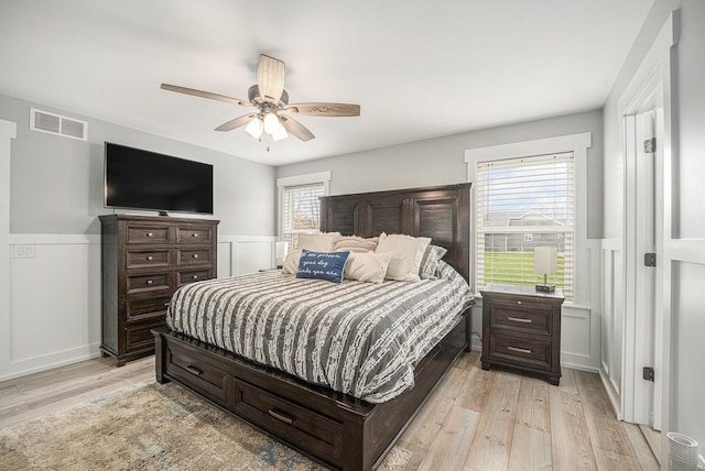 1749 Fairview Dr, Allegan, MI 49010 - bedroom featuring wainscoting, light wood-type flooring, multiple windows, a ceiling fan, and a decorative wall
