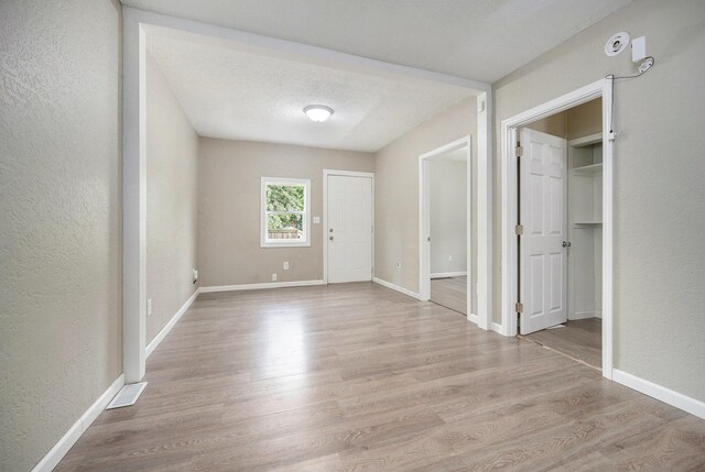 64 E Grand Circle Ave, Battle Creek, MI 49037 - unfurnished dining area with light wood-style flooring, a textured wall, baseboards, and a textured ceiling
