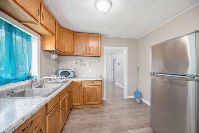 64 E Grand Circle Ave, Battle Creek, MI 49037 - kitchen with freestanding refrigerator, a sink, a textured ceiling, light countertops, and light wood-type flooring