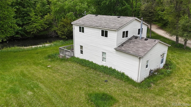 9617 Portage Trl, White Lake, MI 48386 - view of side of home with roof with shingles, a yard, and a forest view