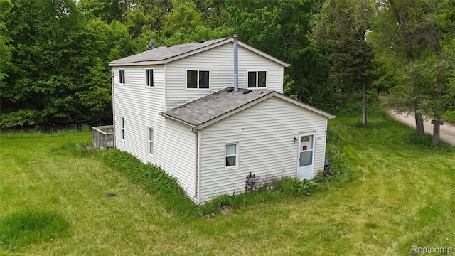 9617 Portage Trl, White Lake, MI 48386 - rear view of property with roof with shingles, a lawn, and a view of trees