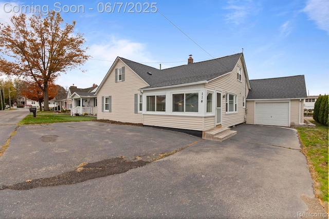 114 Interlochen Dr, Algonac, MI 48001 - view of property exterior featuring driveway, roof with shingles, a chimney, and an attached garage