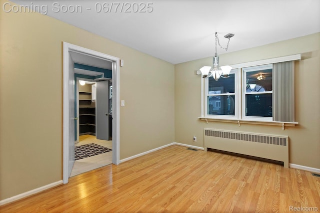 114 Interlochen Dr, Algonac, MI 48001 - empty room with radiator heating unit, a chandelier, light wood-style flooring, and baseboards