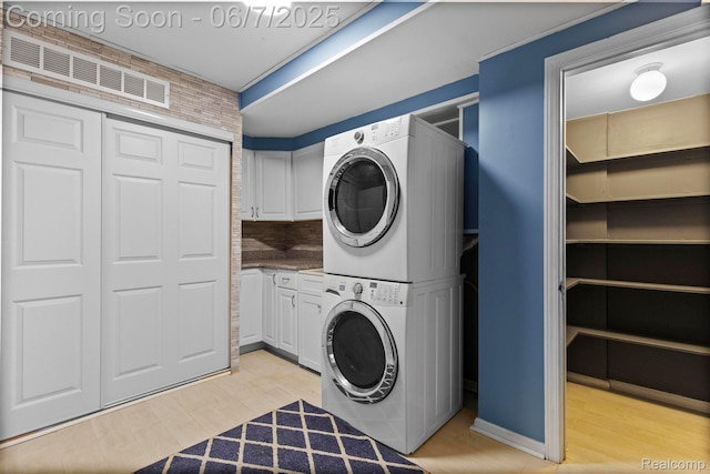 114 Interlochen Dr, Algonac, MI 48001 - laundry room featuring stacked washer / dryer, cabinet space, and light wood finished floors