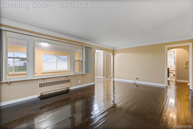 114 Interlochen Dr, Algonac, MI 48001 - unfurnished living room with radiator, arched walkways, hardwood / wood-style floors, and baseboards