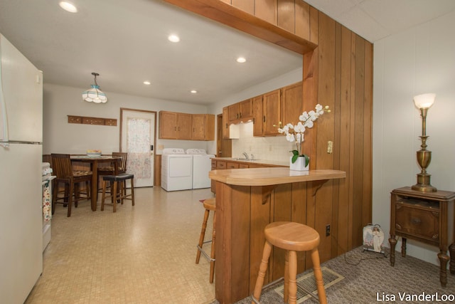 1819 Willis Ave NW, Grand Rapids, MI 49504 - kitchen with washer and dryer, a sink, freestanding refrigerator, brown cabinets, and light countertops