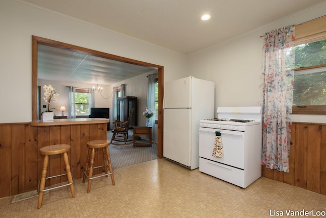 1819 Willis Ave NW, Grand Rapids, MI 49504 - kitchen with white appliances, light flooring, a chandelier, a kitchen bar, and ornamental molding