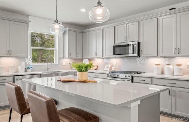 709 Risdon Trl S, Saline, MI 48176 - kitchen featuring appliances with stainless steel finishes, a sink, a kitchen breakfast bar, a kitchen island, and decorative light fixtures