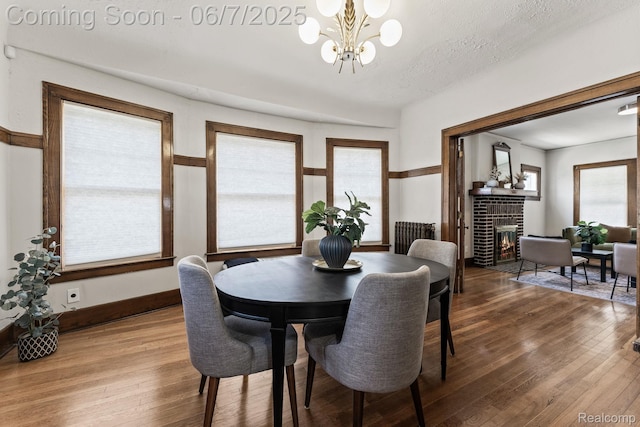 5302 Burns St, Detroit, MI 48213 - dining space with a chandelier, a brick fireplace, wood finished floors, and baseboards