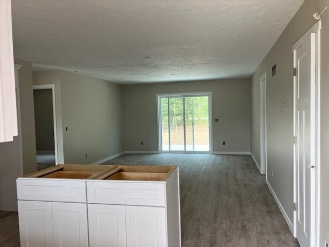 F Walton Rd, Kingsley, MI 49649 - kitchen featuring a textured ceiling, white cabinetry, baseboards, wood finished floors, and open floor plan