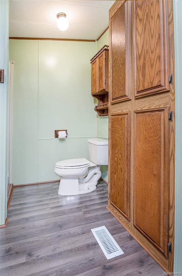 5730 Cavendar Dr, Mount Pleasant, MI 48883 - bathroom featuring toilet, wood finished floors, and ornamental molding