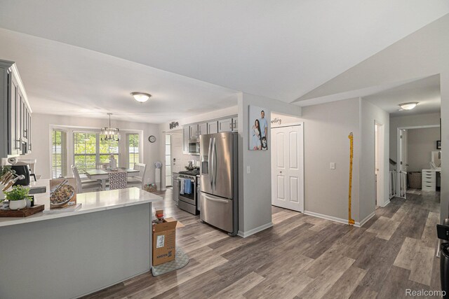 816 Nelsons Ridge Dr, Howell, MI 48843 - kitchen with stainless steel appliances, gray cabinetry, light countertops, wood finished floors, and a chandelier
