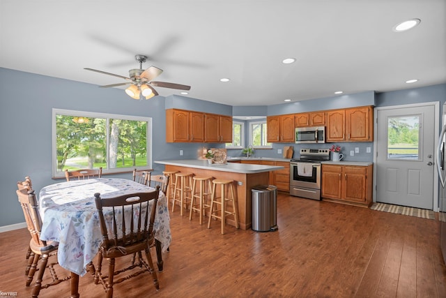 2284 E Frances Rd, Clio, MI 48420 - kitchen with appliances with stainless steel finishes, dark wood-style floors, a peninsula, a kitchen breakfast bar, and light countertops