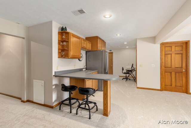 6574 Gran Via Dr NE, Rockford, MI 49341 - kitchen with light carpet, open shelves, freestanding refrigerator, a breakfast bar, and baseboards
