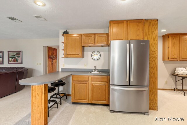 6574 Gran Via Dr NE, Rockford, MI 49341 - kitchen featuring freestanding refrigerator, light colored carpet, a sink, a peninsula, and a breakfast bar area