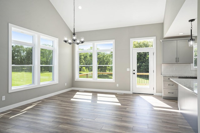 233 Markus Glen Dr, Plainwell, MI 49080 - unfurnished dining area featuring a chandelier, healthy amount of natural light, wood finished floors, lofted ceiling, and recessed lighting