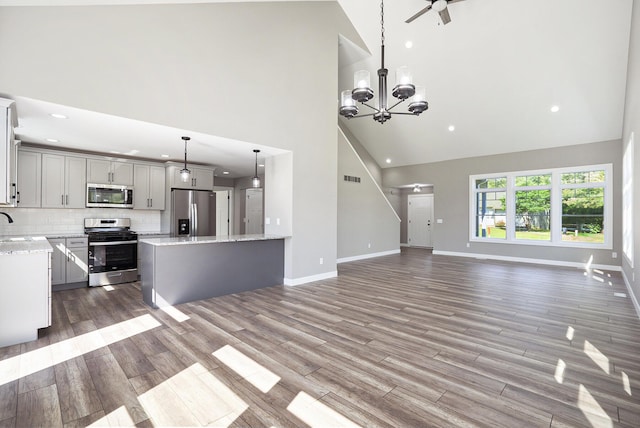 233 Markus Glen Dr, Plainwell, MI 49080 - unfurnished living room featuring high vaulted ceiling, baseboards, wood finished floors, recessed lighting, and ceiling fan