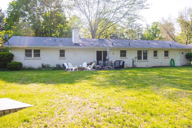4873 Terrace Ln, Saint Joseph, MI 49085 - back of house featuring brick siding, a yard, a chimney, and an outdoor fire pit