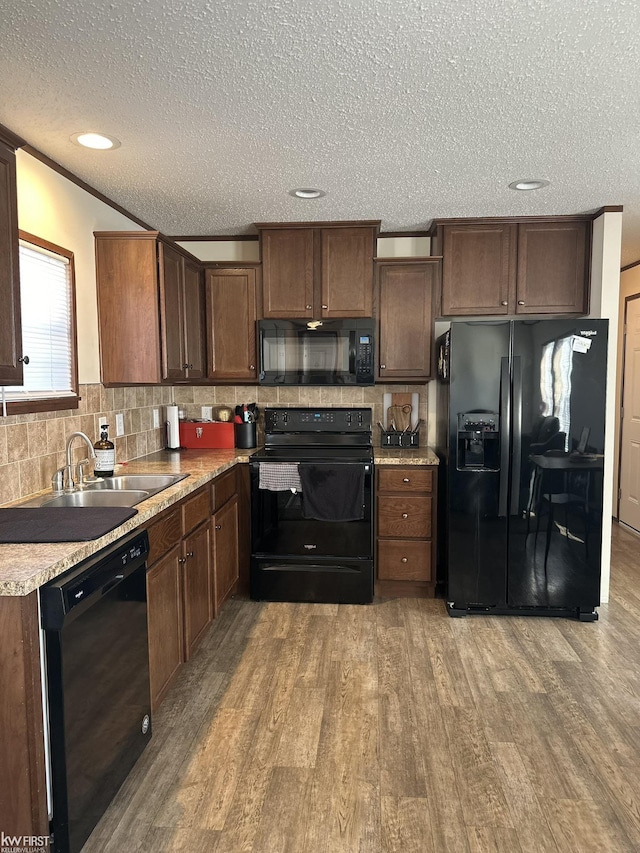 2371 Maple Dr, Fenton, MI 48430 - kitchen with black appliances, a sink, a textured ceiling, wood finished floors, and backsplash
