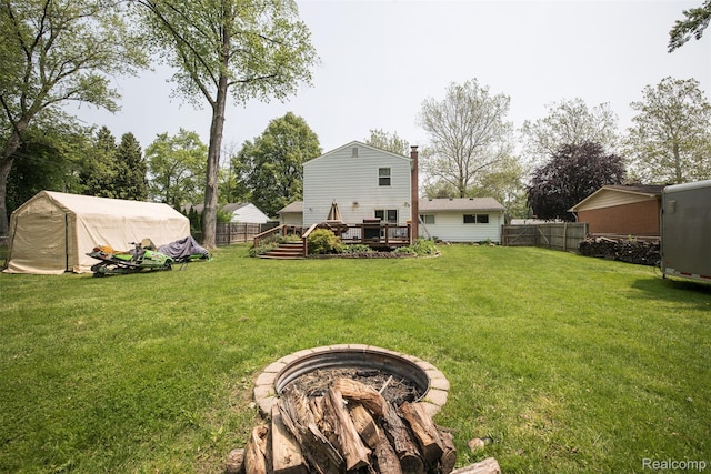 17733 Deering St, Livonia, MI 48152 - back of property featuring a fire pit, a fenced backyard, a deck, an outbuilding, and a chimney