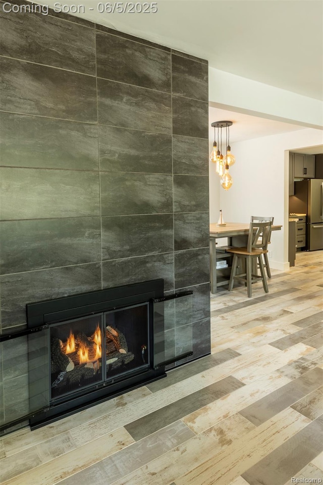 343 Beaupre Ave, Grosse Pointe Farms, MI 48236 - detailed view of a lit fireplace, freestanding refrigerator, wood finished floors, baseboards, and a chandelier