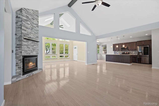 12150 Shaffer Rd, Davisburg, MI 48350 - unfurnished living room featuring a fireplace, light wood-style floors, beam ceiling, ceiling fan, and high vaulted ceiling