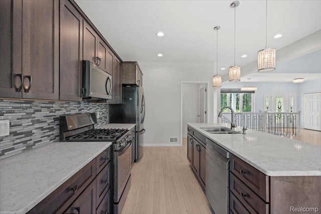 12150 Shaffer Rd, Davisburg, MI 48350 - kitchen featuring appliances with stainless steel finishes, a sink, light wood-style floors, decorative backsplash, and dark brown cabinetry
