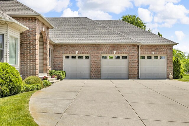 10575 Darrel Dr, Hanover, MI 49241 - view of front of home featuring a garage, a shingled roof, concrete driveway, and brick siding