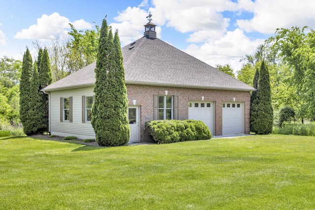 10575 Darrel Dr, Hanover, MI 49241 - view of side of home with a shingled roof, a yard, an attached garage, and brick siding