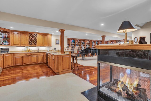 10575 Darrel Dr, Hanover, MI 49241 - kitchen featuring ornate columns, wood finished floors, recessed lighting, brown cabinets, and light stone countertops