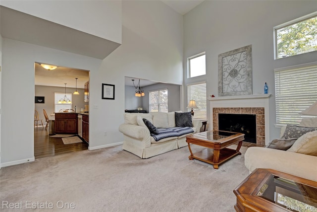 2338 Malena Ln, Oxford, MI 48371 - living room featuring carpet floors, a towering ceiling, baseboards, a tiled fireplace, and healthy amount of natural light