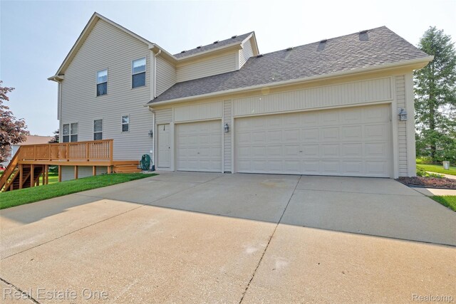 2338 Malena Ln, Oxford, MI 48371 - view of side of property with concrete driveway, an attached garage, roof with shingles, and a wooden deck