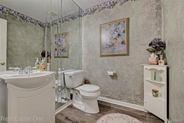 2338 Malena Ln, Oxford, MI 48371 - bathroom with wood finished floors, vanity, toilet, wallpapered walls, and baseboards