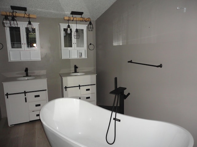 1920 S 15th St, Niles, MI 49120 - bathroom featuring two vanities, a soaking tub, wood finished floors, and a textured ceiling