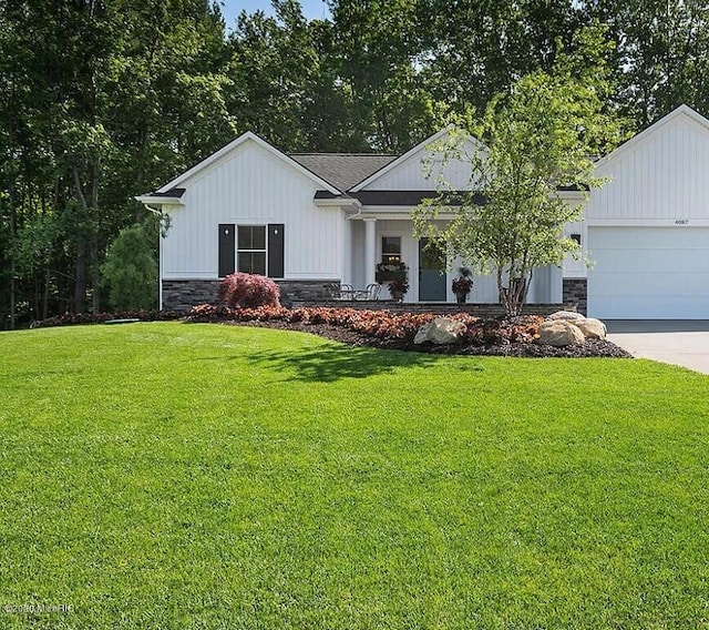 4087 Ronalds Rd, Dorr, MI 49323 - view of front of property featuring stone siding, a front yard, an attached garage, and driveway