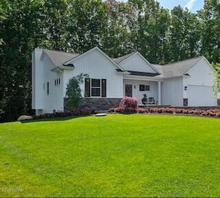 4087 Ronalds Rd, Dorr, MI 49323 - view of front of home with a front yard, an attached garage, and stone siding