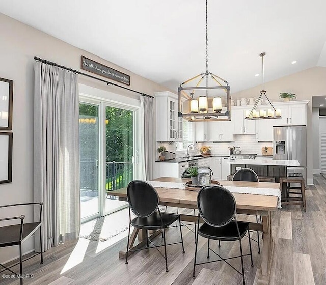 4087 Ronalds Rd, Dorr, MI 49323 - dining space with a chandelier, light wood-type flooring, and vaulted ceiling