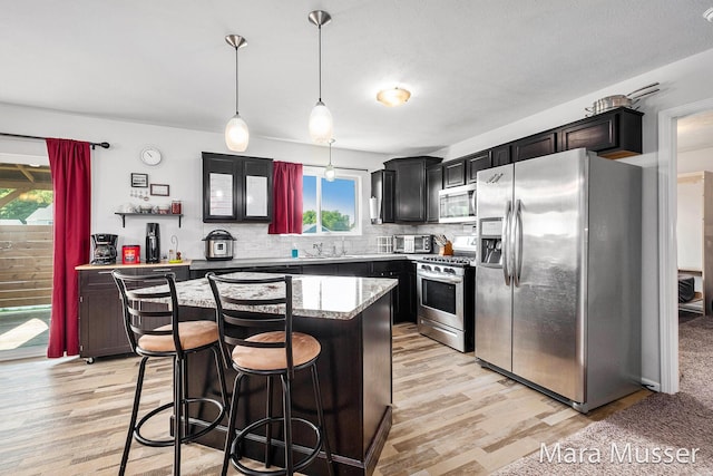 310 Robin Ct, Caledonia, MI 49316 - kitchen featuring stainless steel appliances, a kitchen island, light wood-style flooring, backsplash, and a breakfast bar