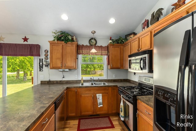 11185 Stanton St, West Olive, MI 49460 - kitchen featuring appliances with stainless steel finishes, a sink, dark countertops, brown cabinets, and light wood-style flooring