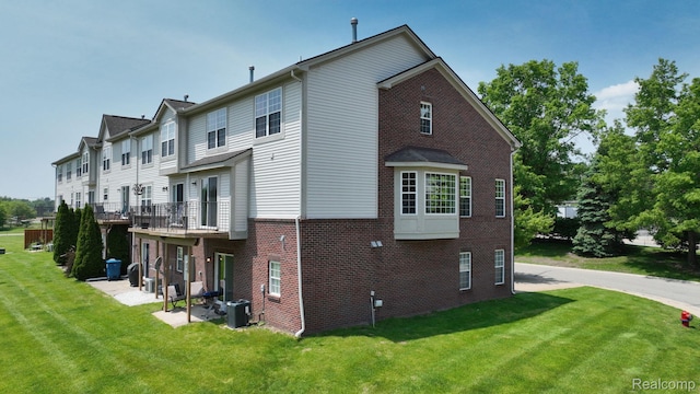 71 Grandview Cir, White Lake, MI 48386 - view of side of property with brick siding, a lawn, central air condition unit, and a patio area