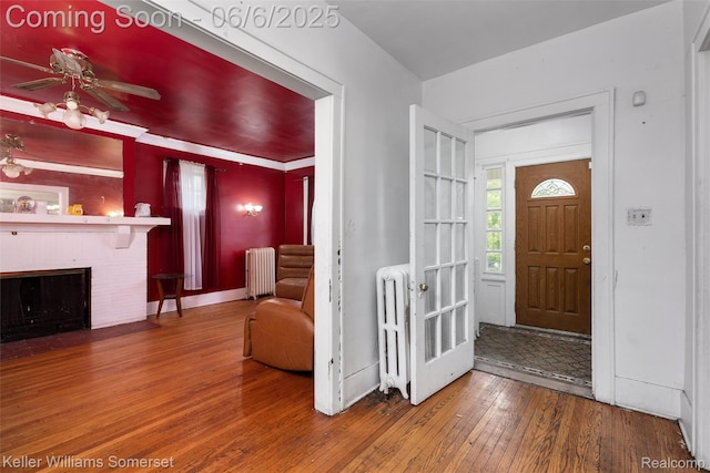 1475 Atkinson St, Detroit, MI 48206 - entrance foyer with radiator, wood-type flooring, a brick fireplace, and a ceiling fan