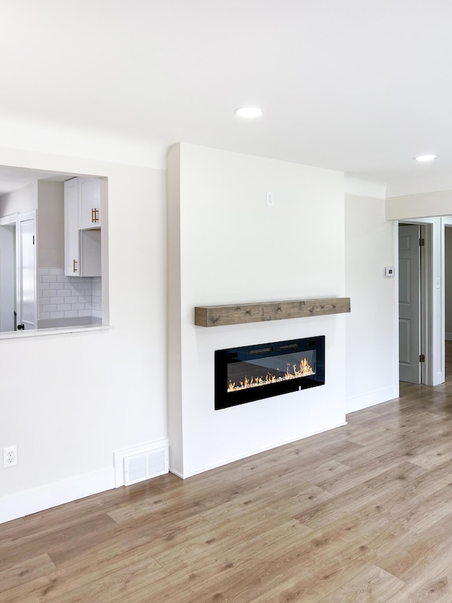 20215 Damman St, Harper Woods, MI 48225 - unfurnished living room featuring a glass covered fireplace, light wood-style floors, recessed lighting, and baseboards