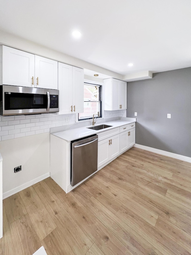 20215 Damman St, Harper Woods, MI 48225 - kitchen with stainless steel appliances, a sink, light wood finished floors, white cabinetry, and light countertops