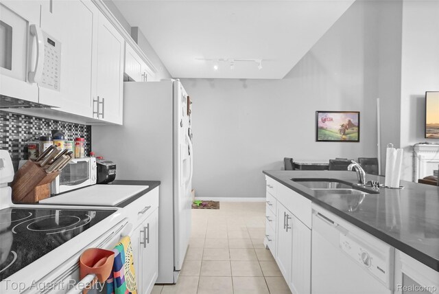 11685 Squiers Blvd, Utica, MI 48315 - kitchen with white appliances, dark countertops, rail lighting, white cabinets, and light tile patterned flooring
