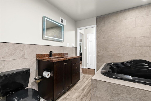2128 Somerset Rd, Bloomfield Hills, MI 48302 - full bath with tile walls, wood finished floors, a garden tub, toilet, and vanity