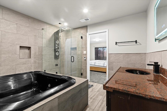 2128 Somerset Rd, Bloomfield Hills, MI 48302 - ensuite bathroom featuring a shower stall, a tub with jets, vanity, tile walls, and wood finished floors