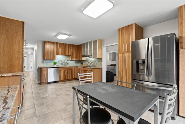 2128 Somerset Rd, Bloomfield Hills, MI 48302 - kitchen with appliances with stainless steel finishes, brown cabinetry, backsplash, a sink, and glass insert cabinets